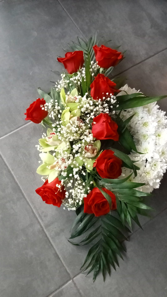 Un aranjament floral realizat din trandafiri rosii, orhidee verde si crizantema