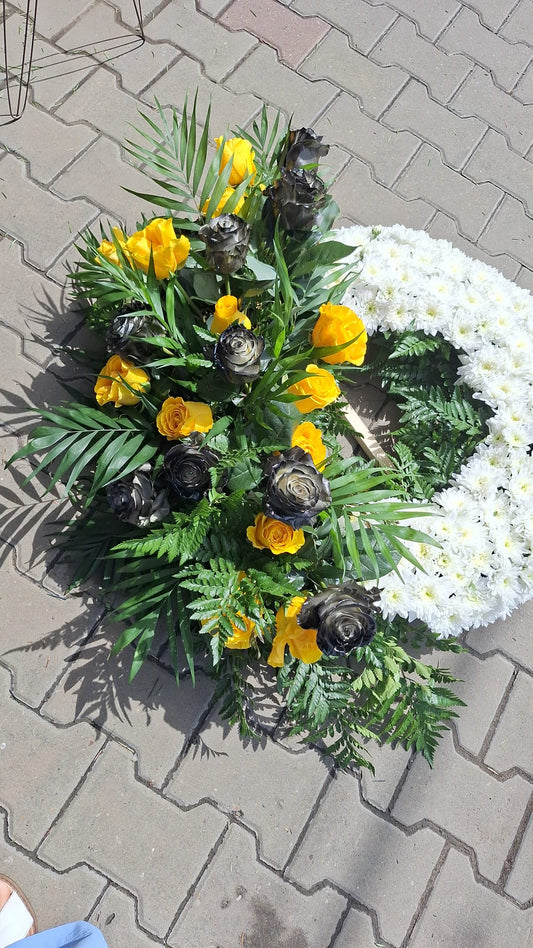 Aranjament realizat din crizanteme albe, trandafiri galbeni si trandafiri negri, completate de verdeata naturala